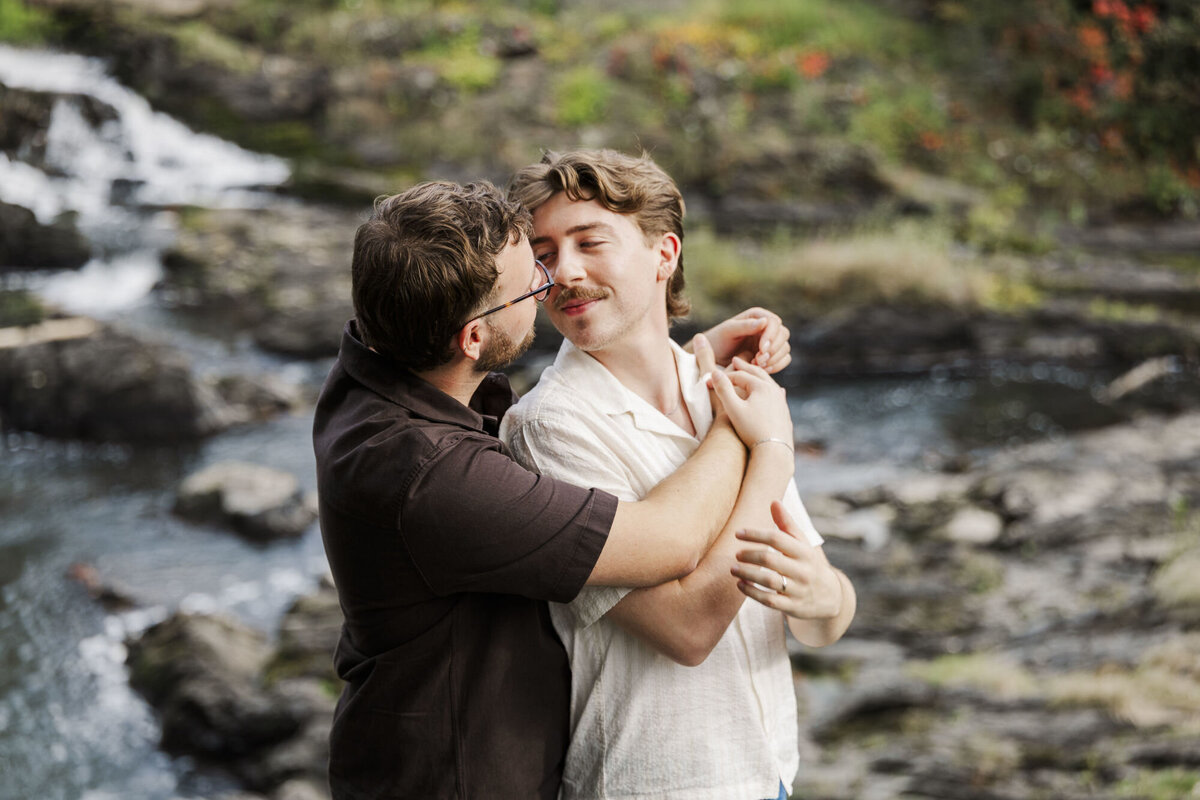 Couple embracing beside a waterfall during Hudson Valley engagement photos