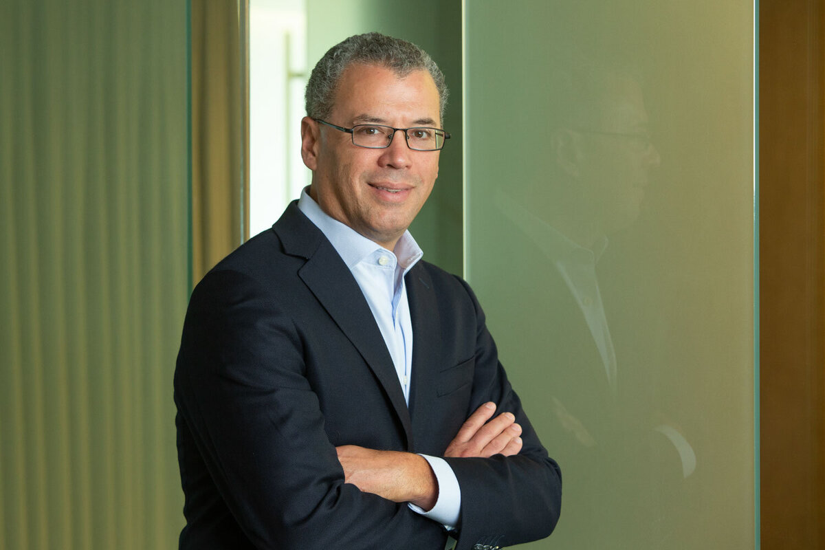 Man in suit posing with arms crossed by glass wall