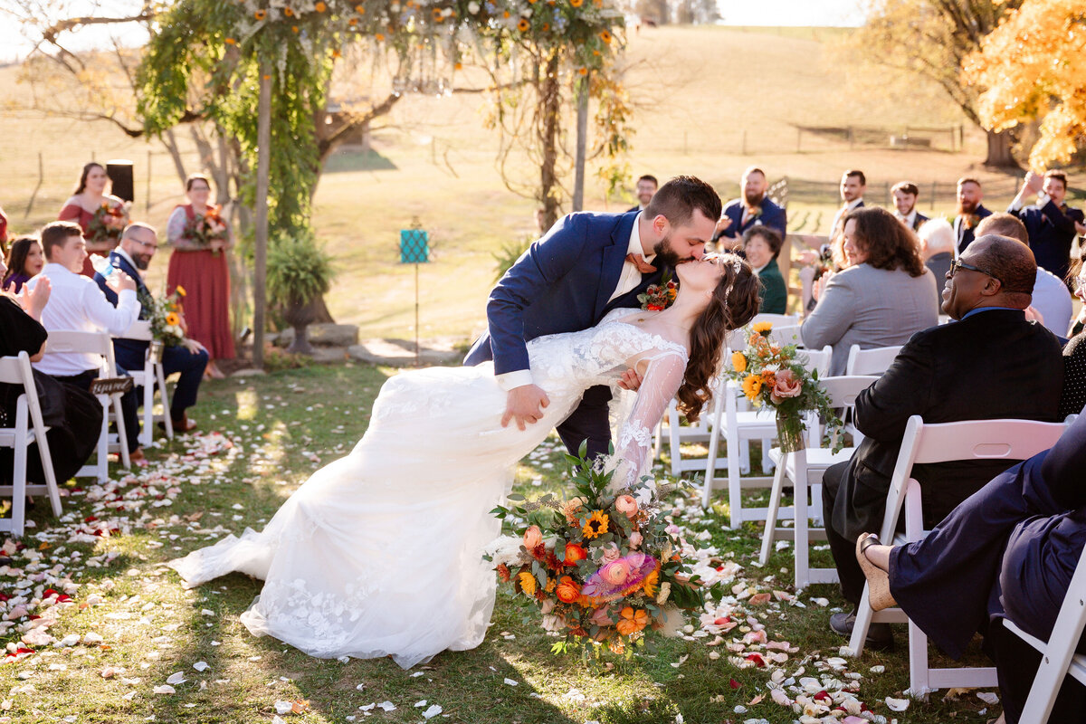 wedding ceremony kissing couple at end of the aisle outside of shady elms farm
