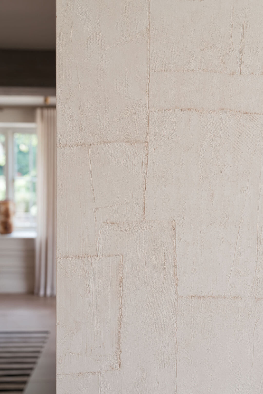 A close-up view of a the neutral textured wallpaper in the cozy living room.