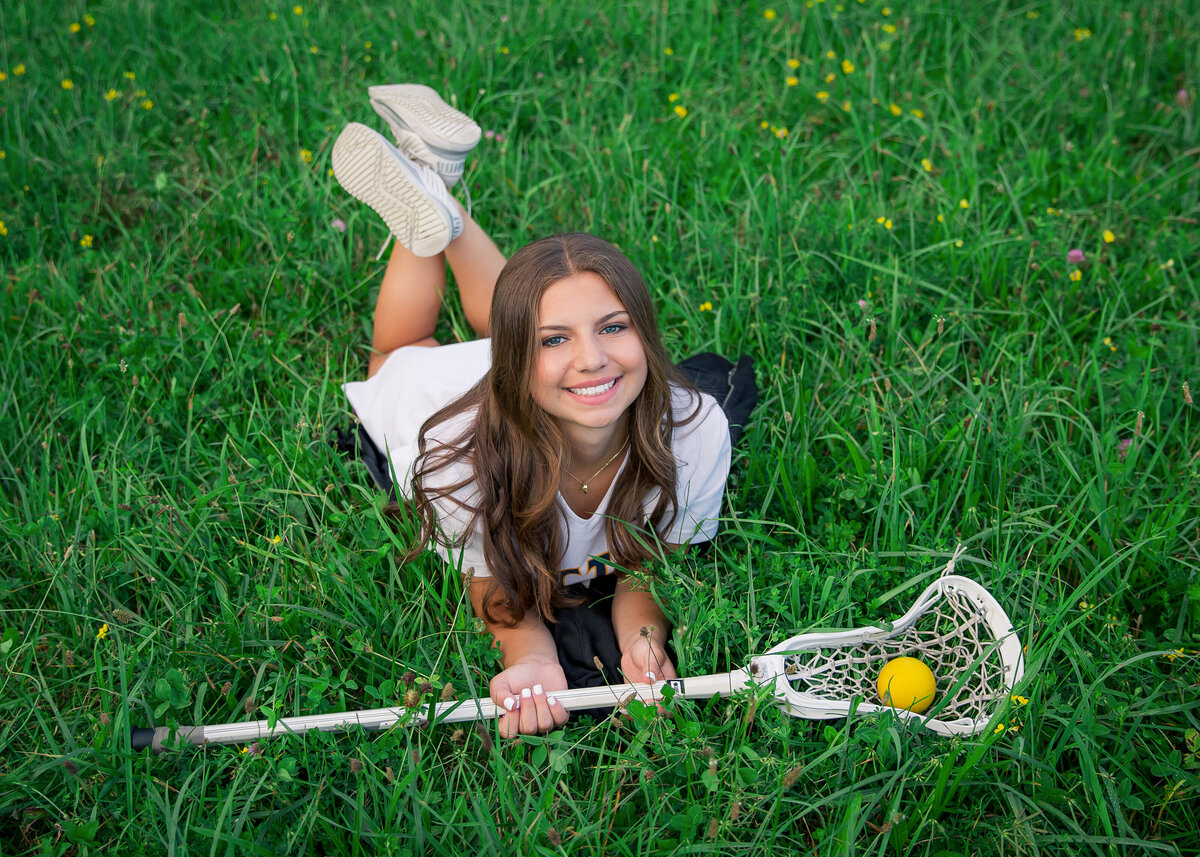 Lacrosse Senior pictures taken of a girl wearing her lax uniform from Victor, NY in a field