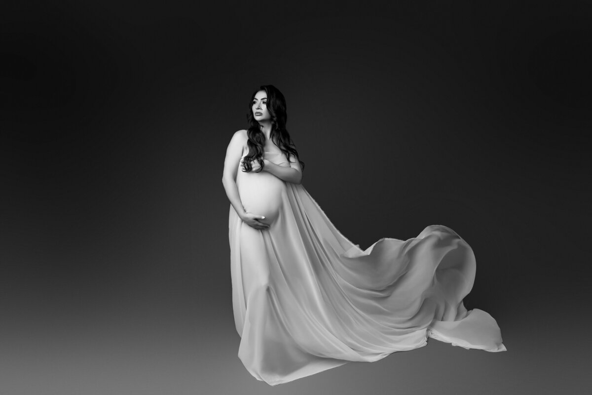 Pregnant woman posing in lux chiffon fabric for maternity session in phoenix maternity studio 