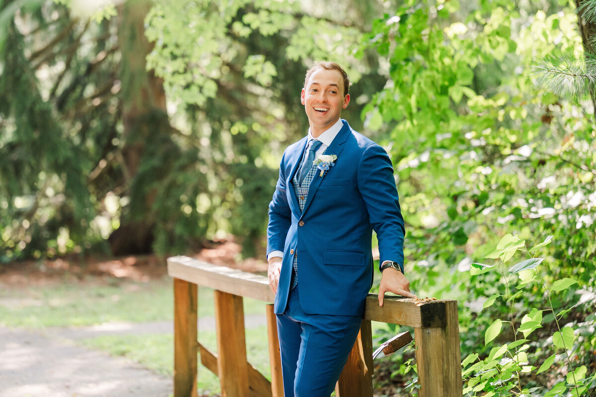 groom posing for wedding photo on the bridge at the YMCA Camp Kon-O-Kwee lake