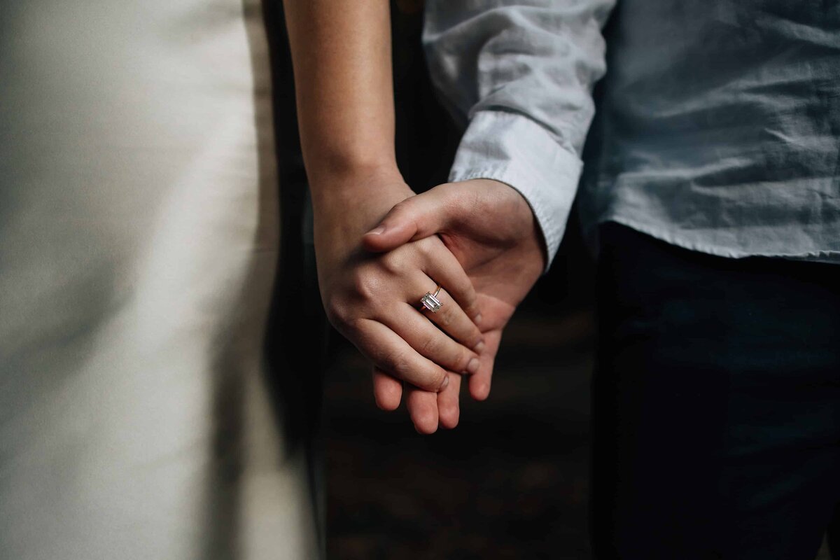 Engagement photoshoot image of couple holding hands, diamond engagement ring clearly shown, And So I Don't Forget Photography