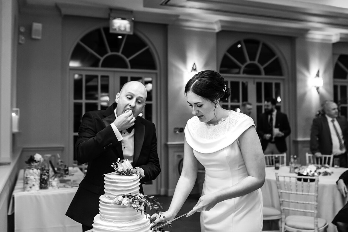 Bride cutting the cake while the groom eats some