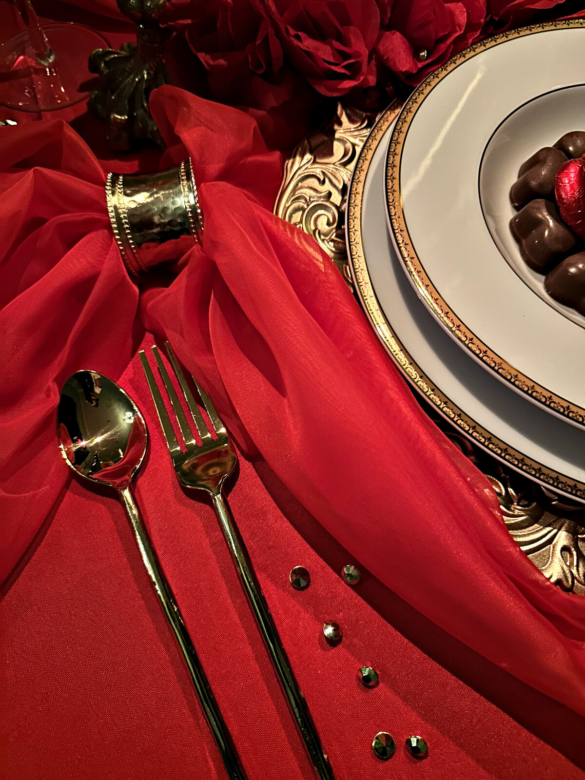 "Love is in the Air" themed tablescape featuring rich red décor, elegant table settings, and lush floral arrangements, designed by In Full Bloom Event Planning & Design