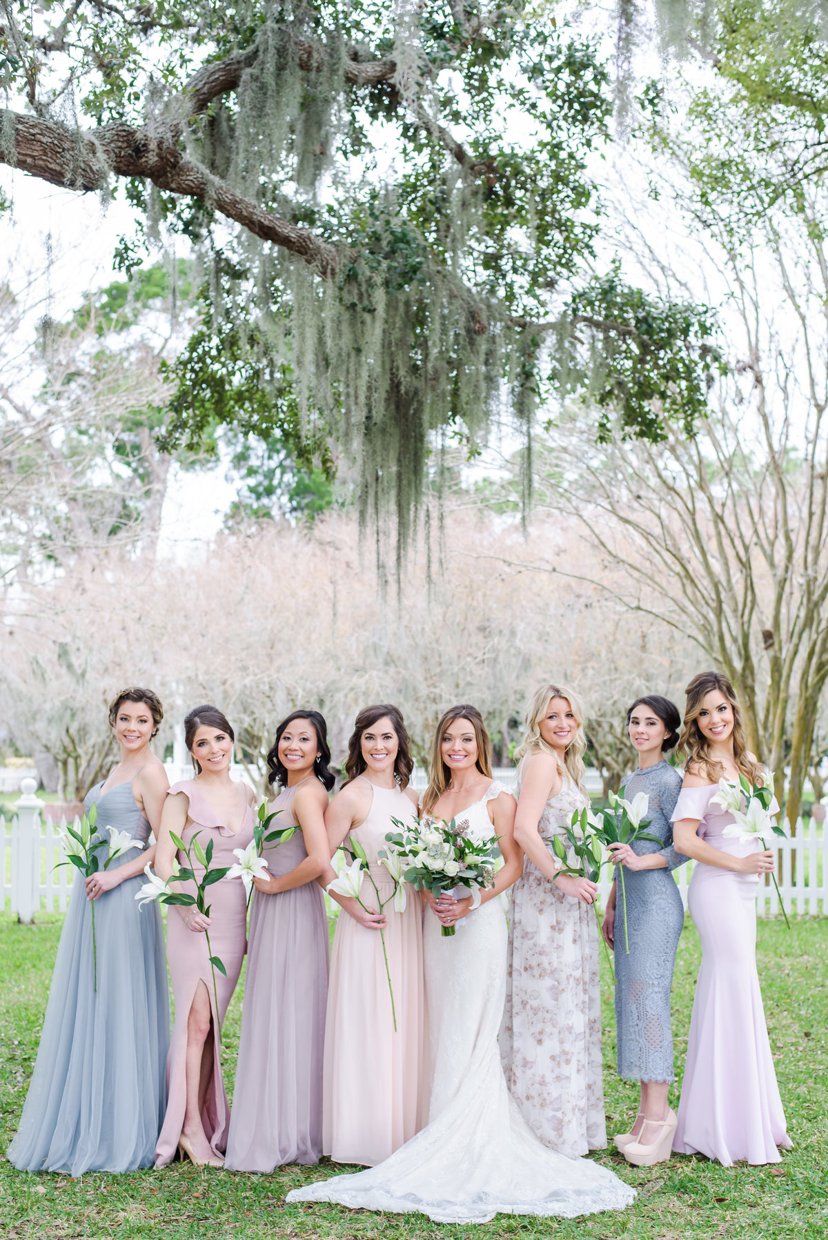 Bride and her pastel dressed Bridesmaids pose holding simple florals outside the Palmetto Bed and Breakfast