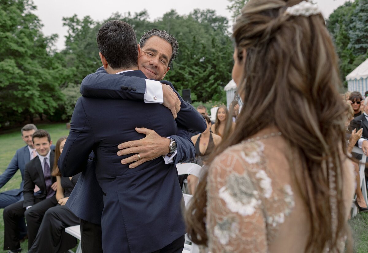 Father embraces Groom during wedding ceremony in Newport.