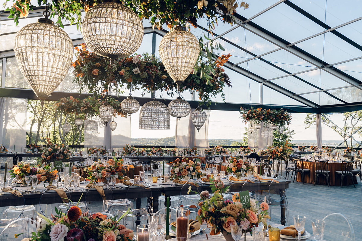Tasteful fall florals for private property wedding in the foothills of Tennessee. Black rimmed clear tent wedding in Nashville, TN. Fall floral centerpieces consisting of dahlias, roses, fall foliage, and protea. Fall wedding colors in rust, copper, sage, gold, and hunter green. Unique pleated and textured candles for wedding tables. Design by Rosemary & Finch Floral Design in Nashville, TN. 