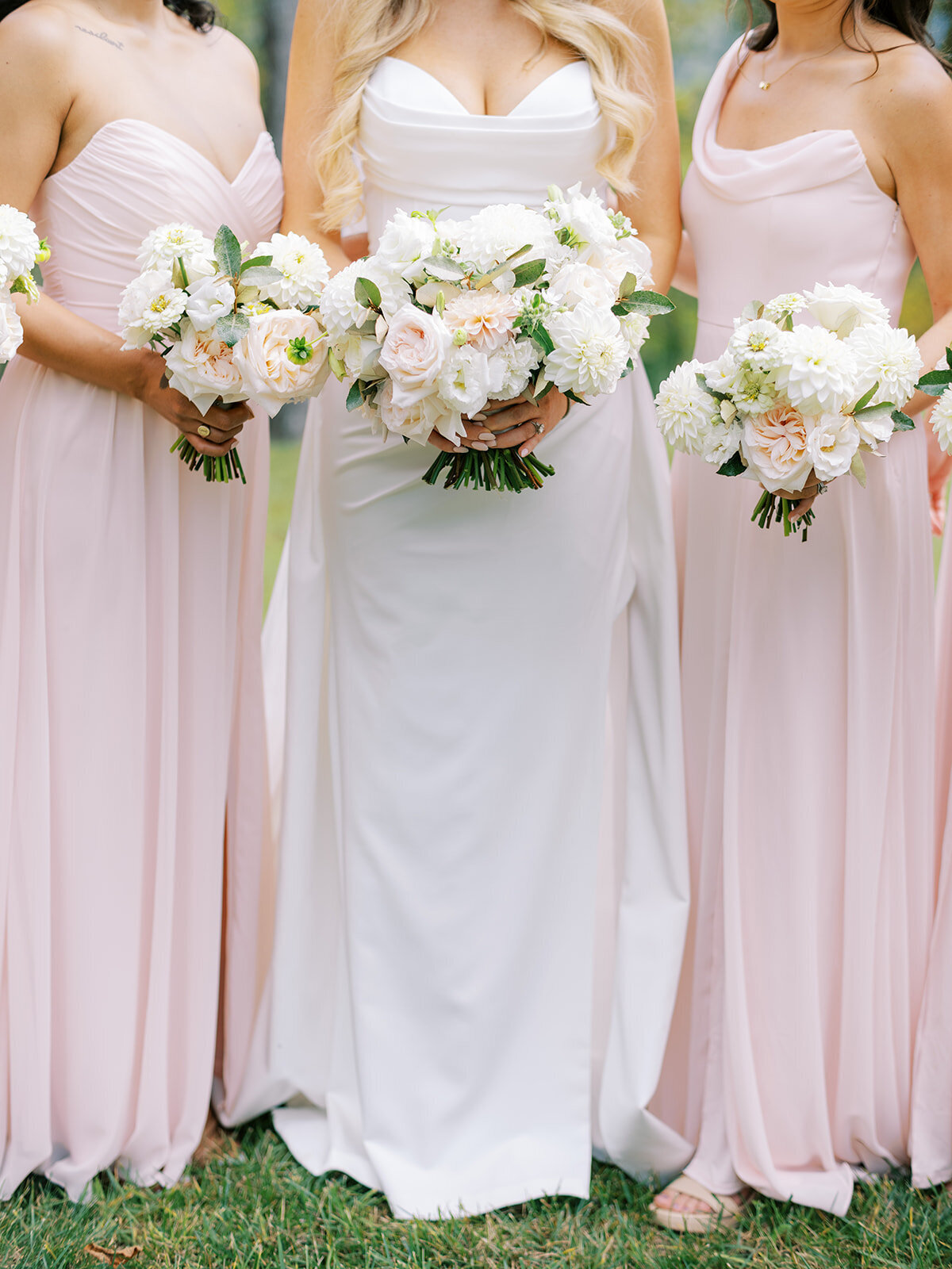 Bride and bridesmaids in soft blush dresses holding white and blush bouquets at The Waynesville Inn & Golf Club in Waynesville, NC.
