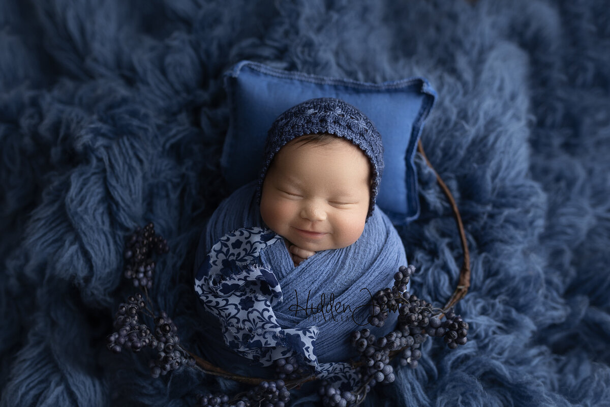Baby wrapped in blue and smiling 