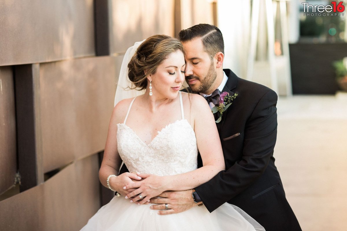 Newly married Groom embraces his Bride from behind as they share a tender moment together