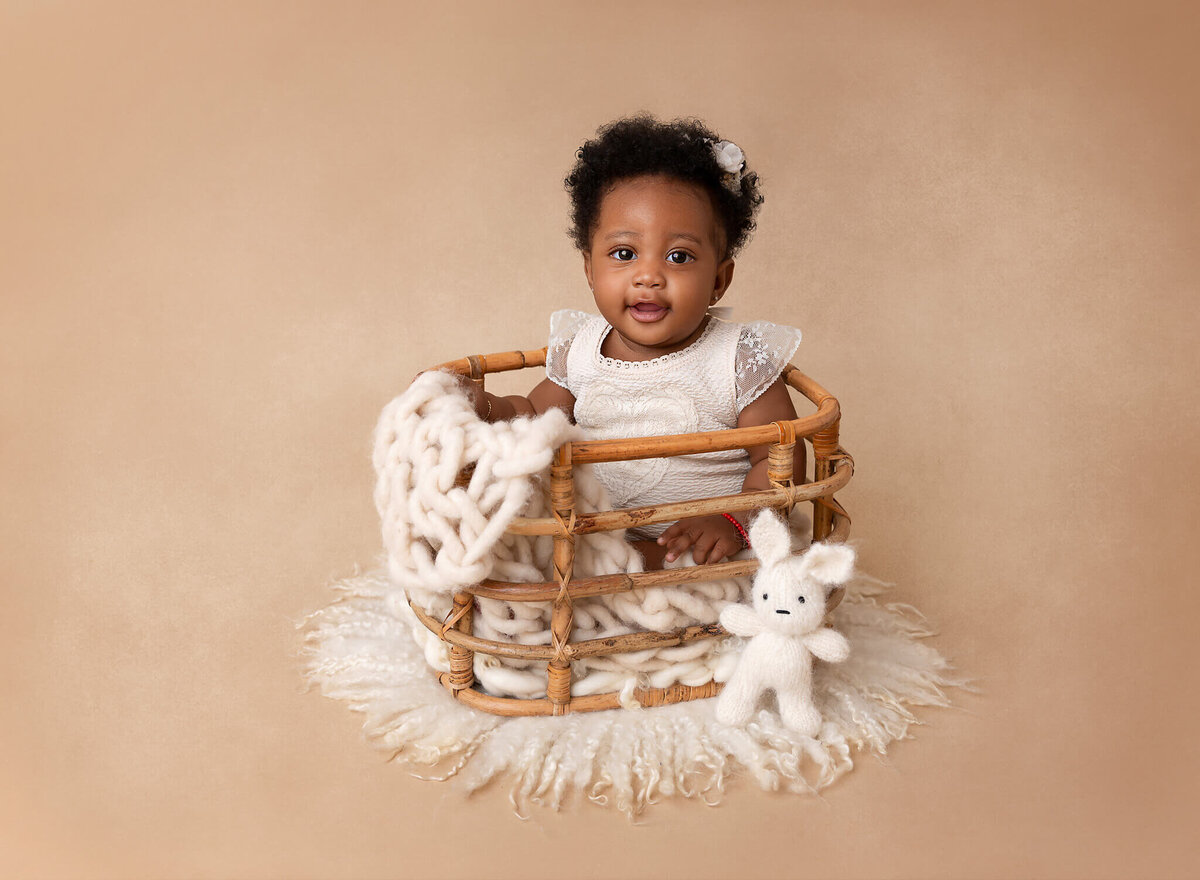 6-month-old baby girl smiling at the camera in a white lace romper during her NYC photoshoot. Expert baby photography in New York City.