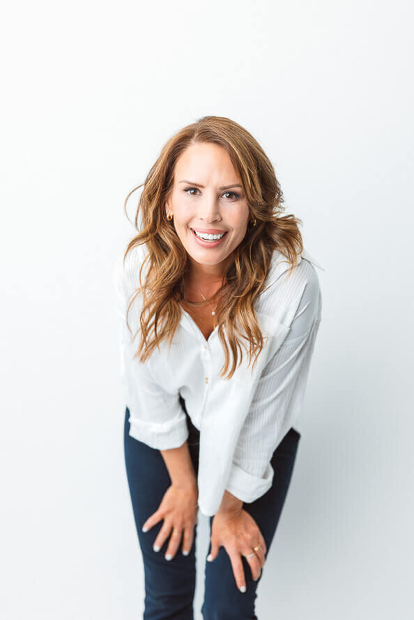 Girl leans over and puts hands on legs for her photo session.