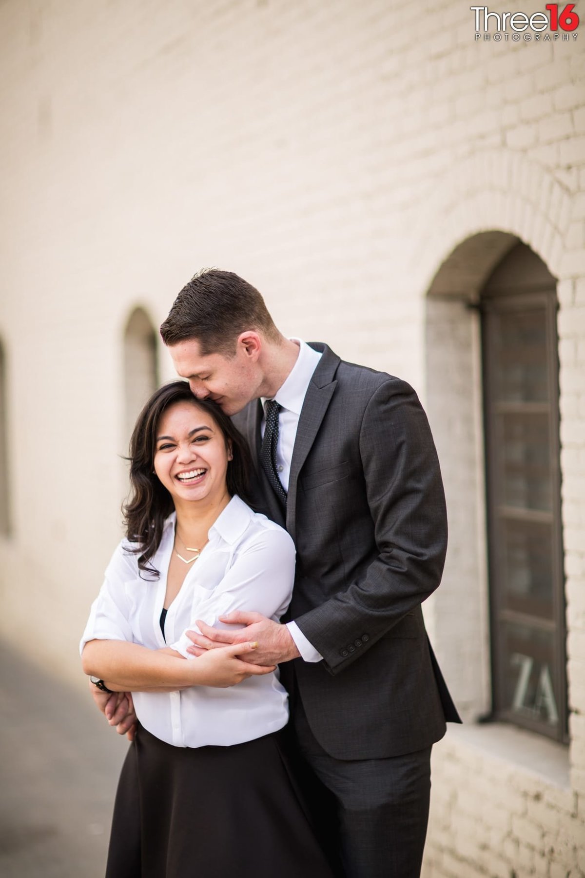 Groom to be embraces his Bride from behind during photo session