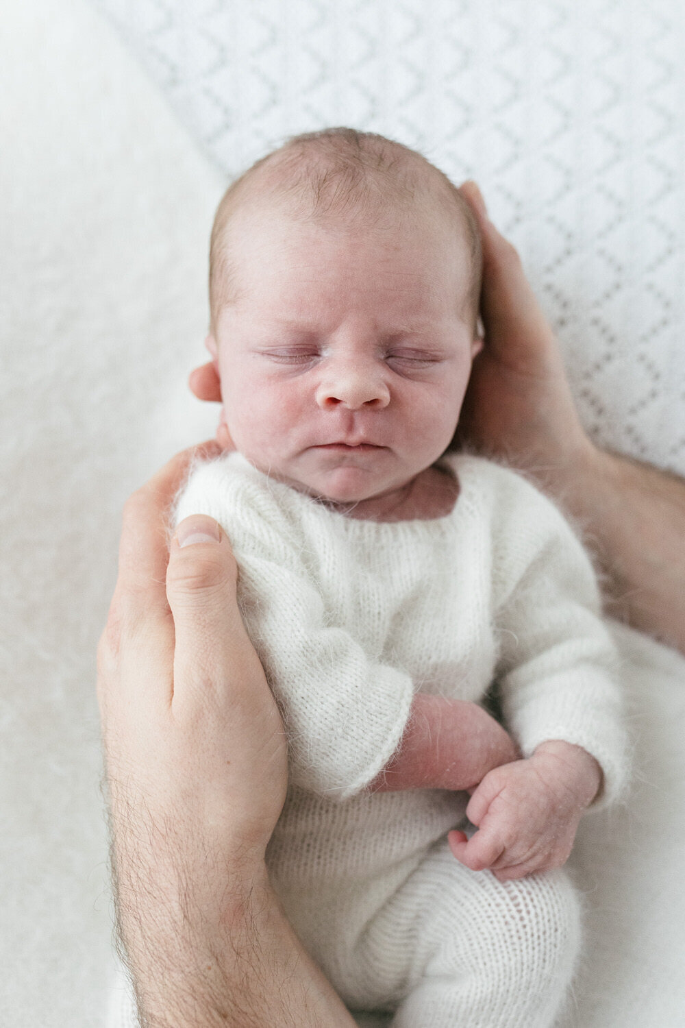 Baby held in dads hands asleep
