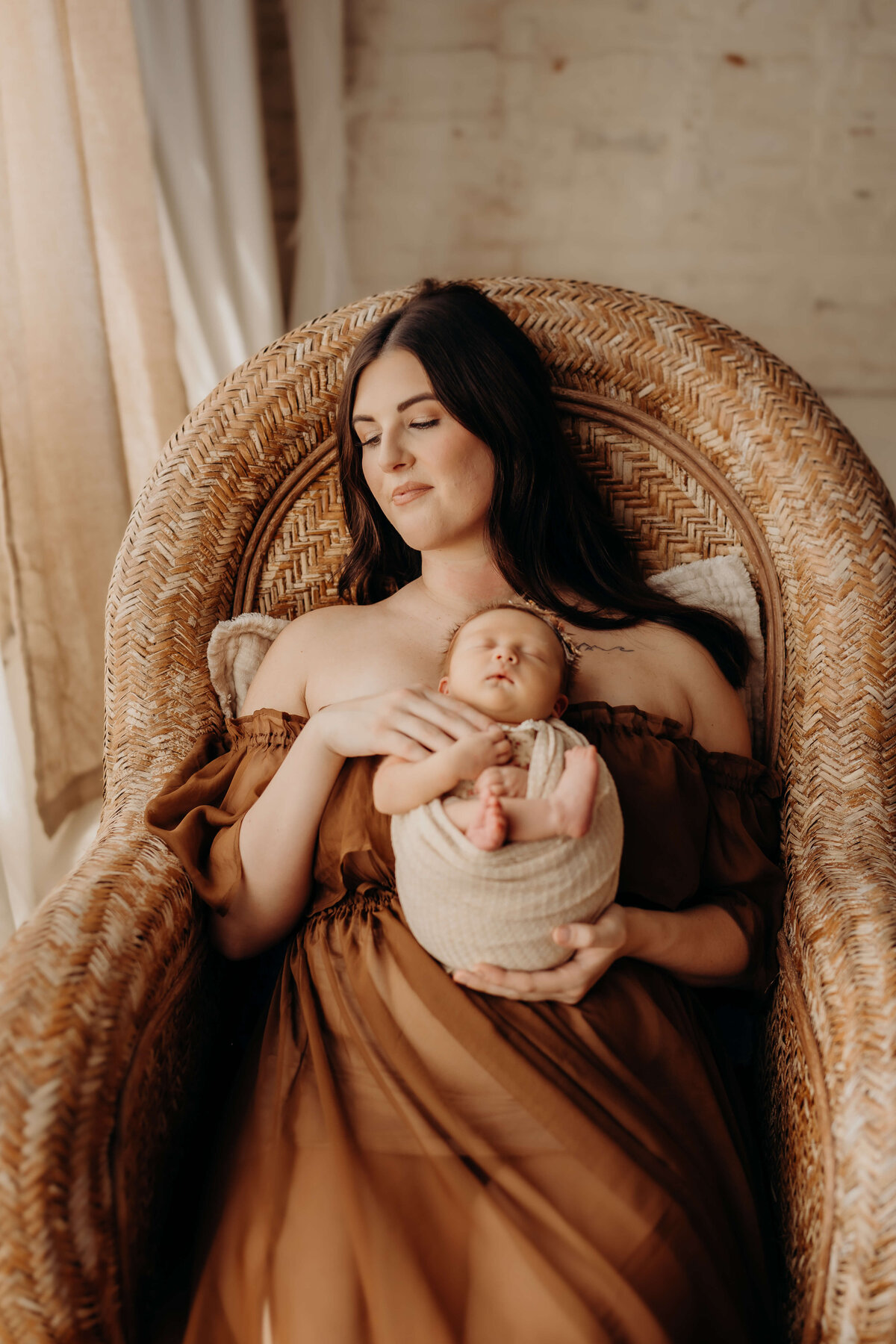 mom holds newborn in a high back wicker chair