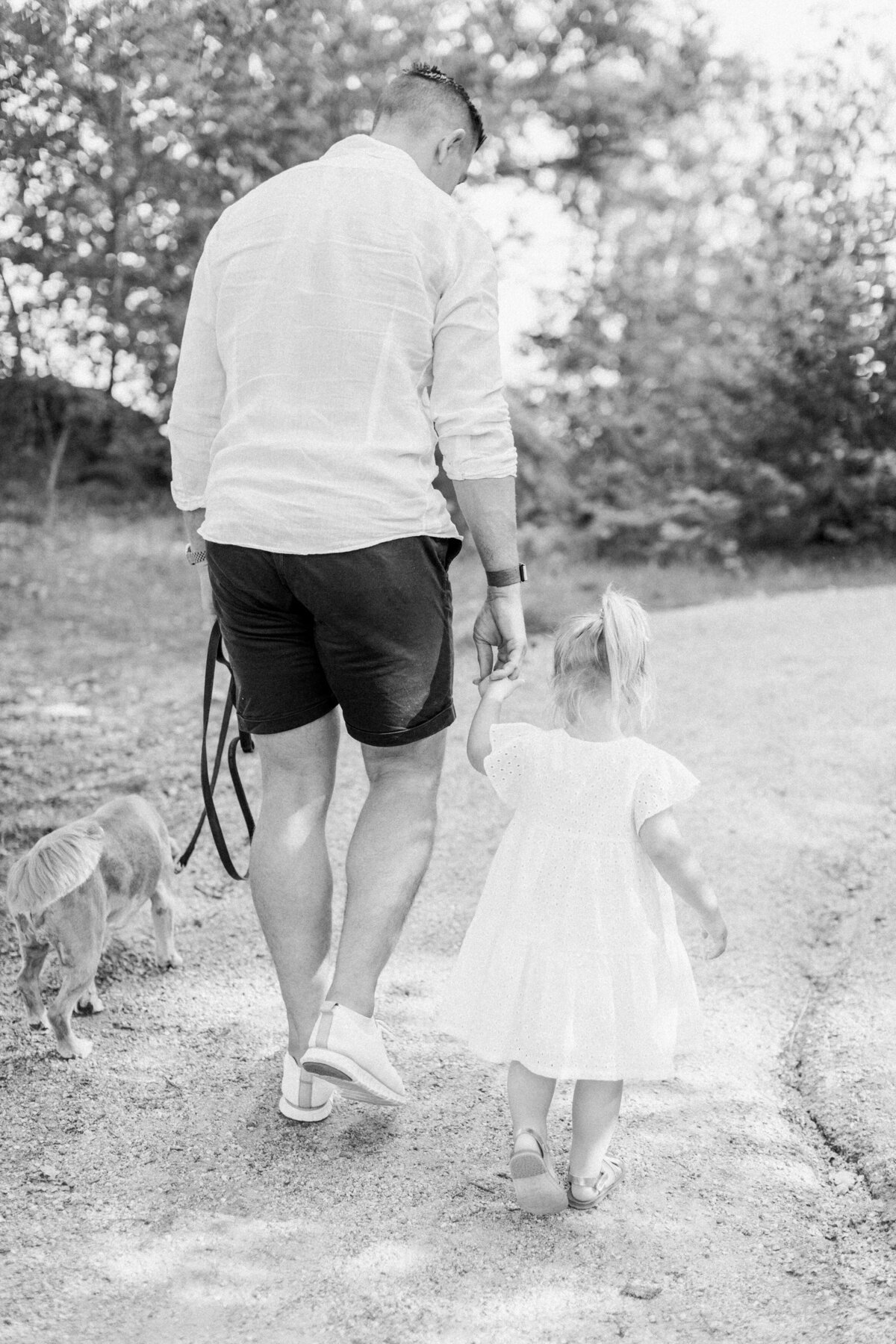 Pappa håller sin dotter i handen när de går på en grusväg
