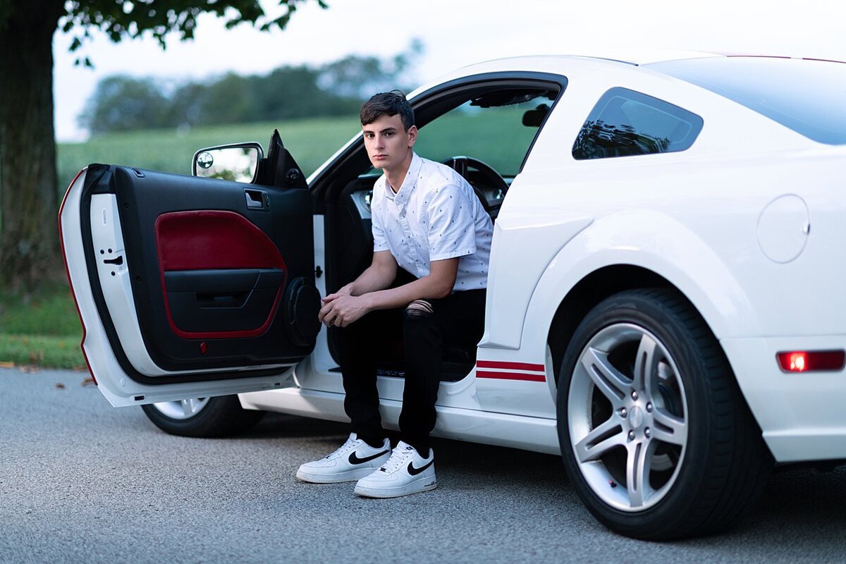 High school senior boy seated in white mustang