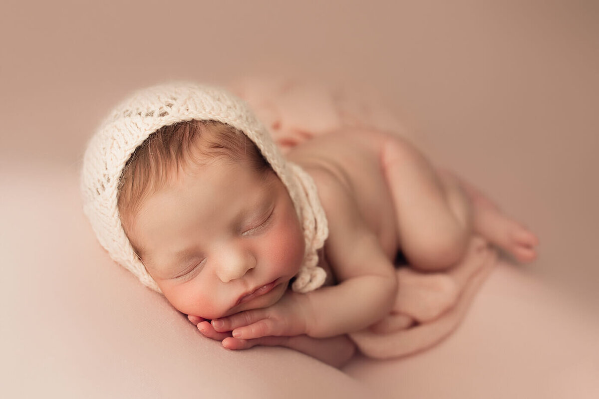 newborn girl side sleeping with both hands under cheek