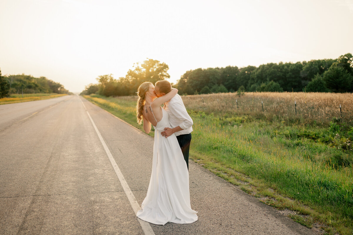 Bride and groom standing in tall grass and trees while holding hands