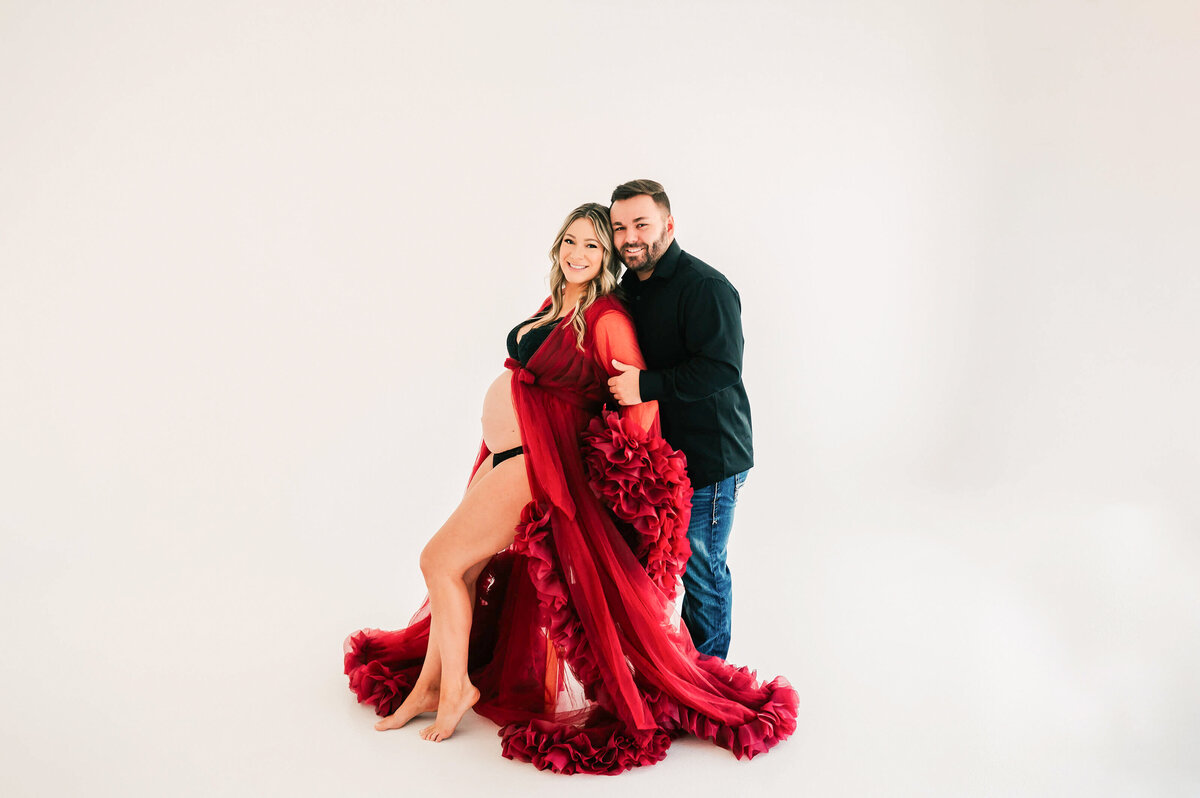 pregnant couple in red robe in maternity photography studio in Springfield MO