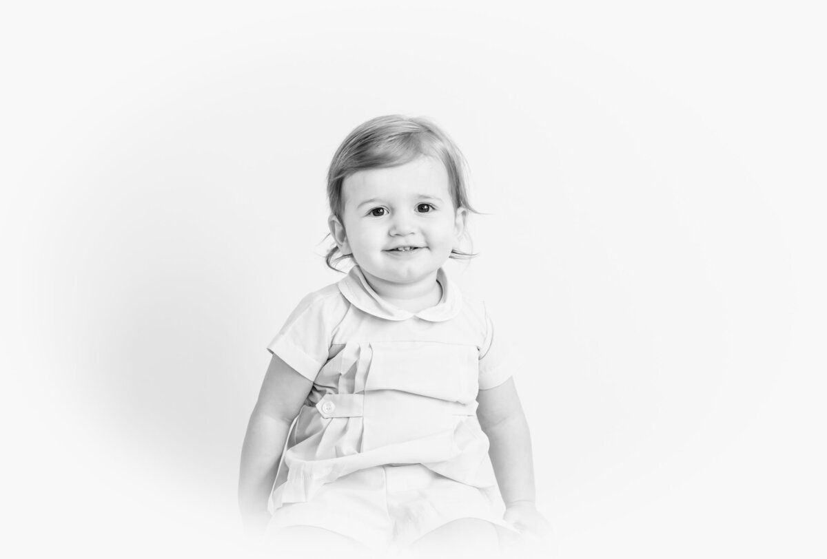 Black and white portrait of a toddler smiling at the camera.