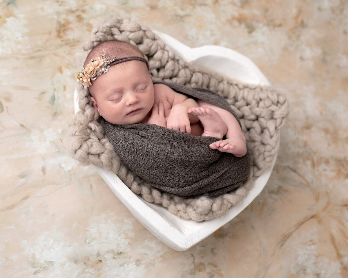 Adorable newborn in a heart-shaped bucket
