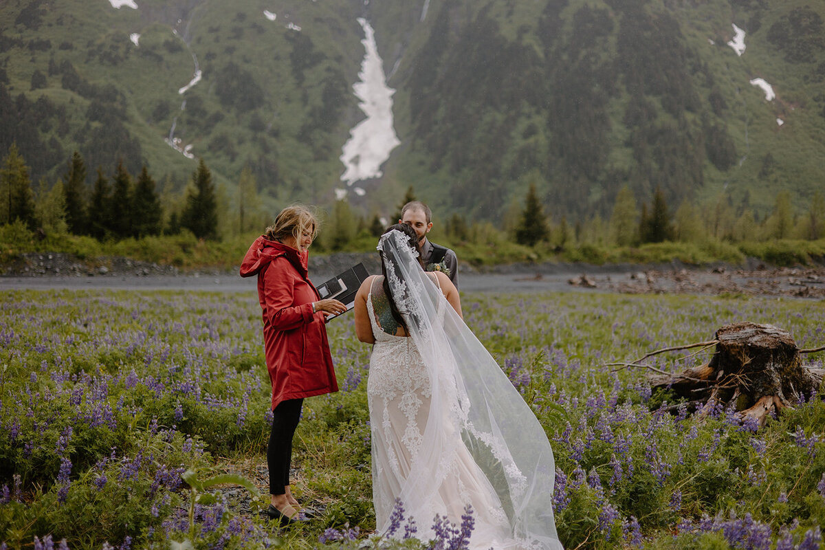 Elopement couple recites vows in flower field with mountain view.