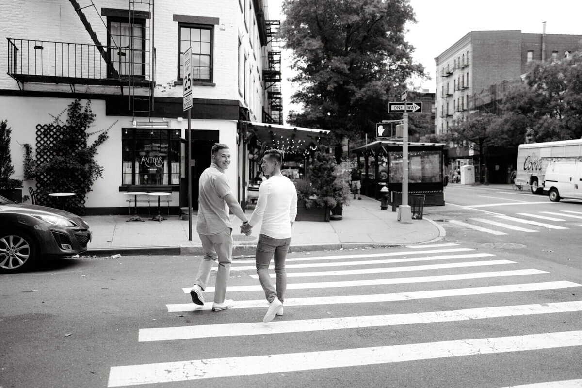 Black and white, back-view photo of the engaged couple crossing the street in West Village, NYC. Image by Jenny Fu Studio