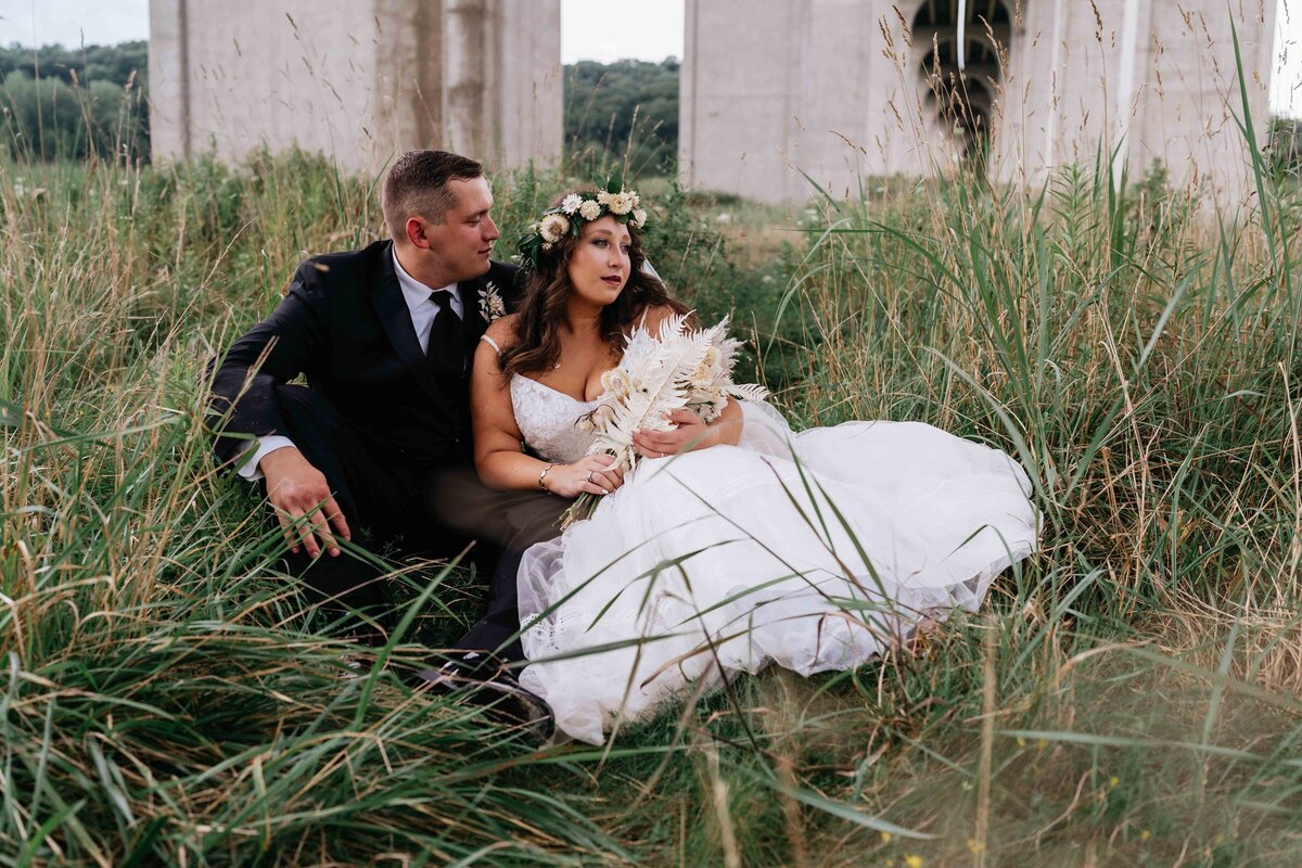 Bride and groom lay in tall grasses