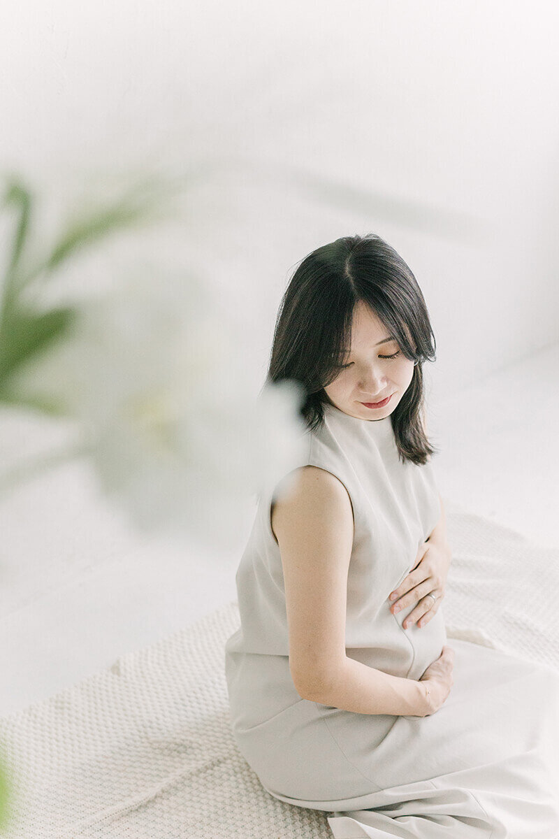 前景に紫陽花が咲いていて、妊婦さんが座った状態で後ろを振り返っている、美しくおしゃれななマタニティフォト。
