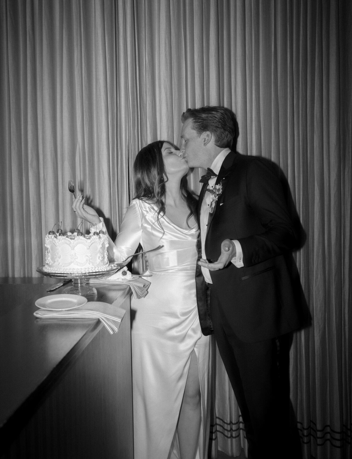 a couple kisses after cutting their wedding cake at Shinola Hotel, Detroit
