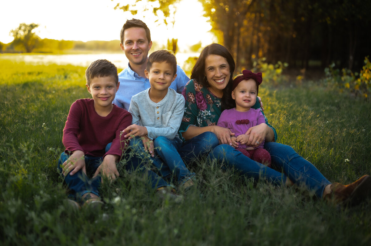 Family laughing together in a grassy field at sunset — joyful Weatherford family photographer Poppy + Blue Photography