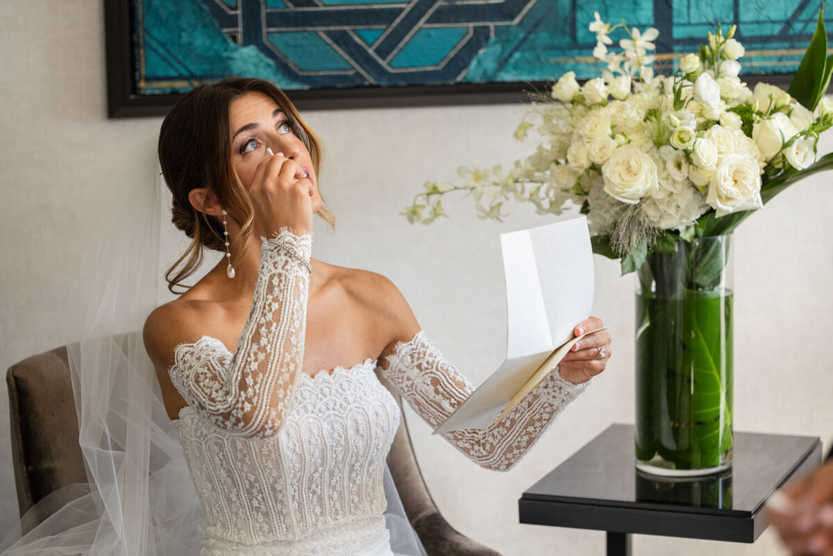 A woman in a white lace dress is holding a piece of paper