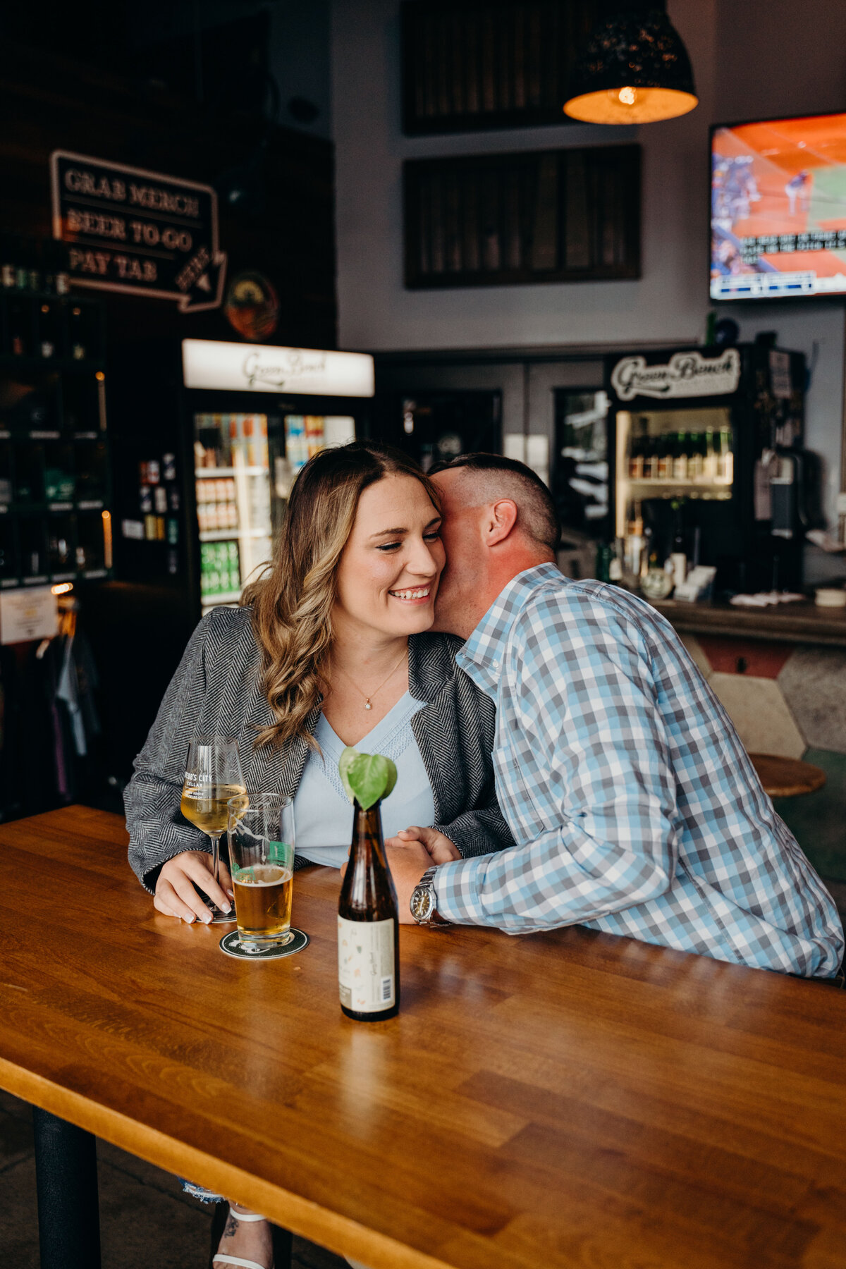couple snuggling at brewery during engagement session in st pete florida