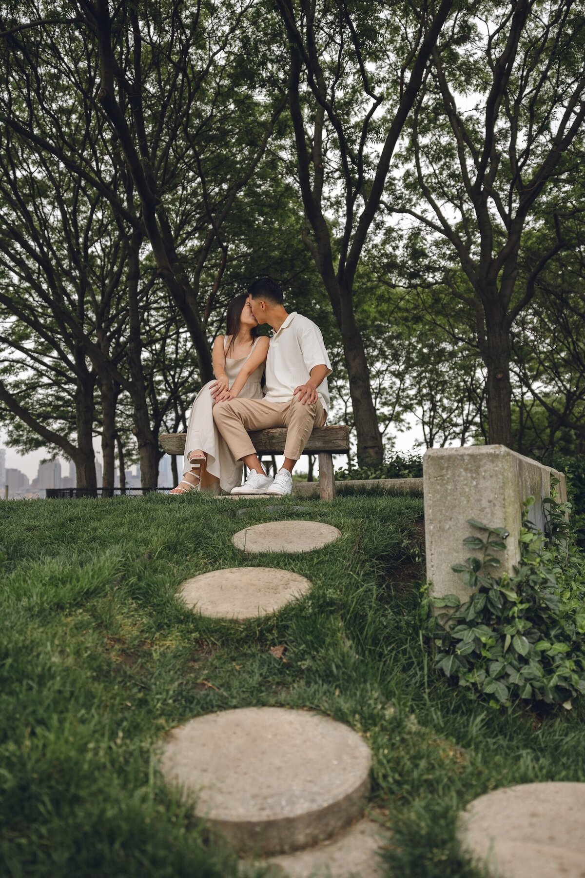 Couple smiling and holding each other on a park bench in Hoboken