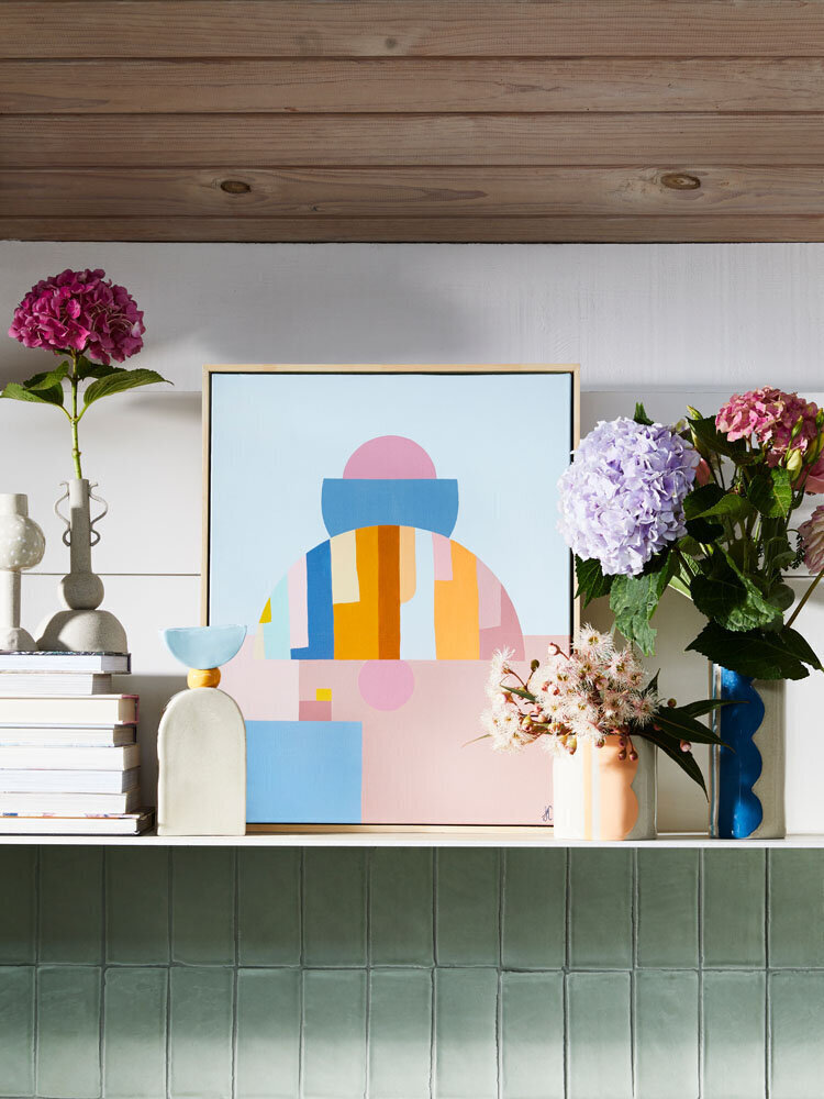Soft pink and beige abstract painting styled with sculptural vases and neutral-toned accessories