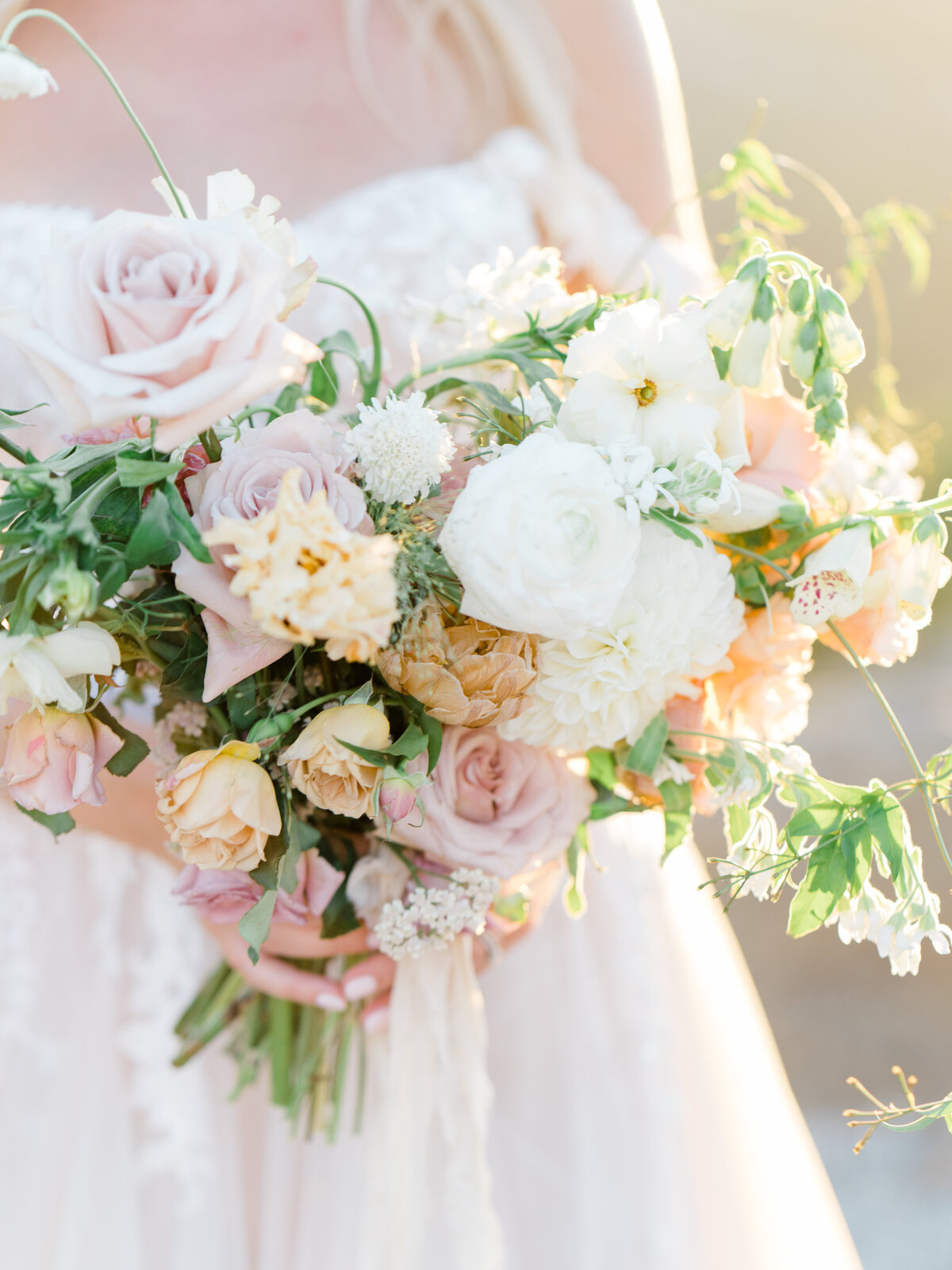 bride holding a bouquet of light yellow pink and white flowers