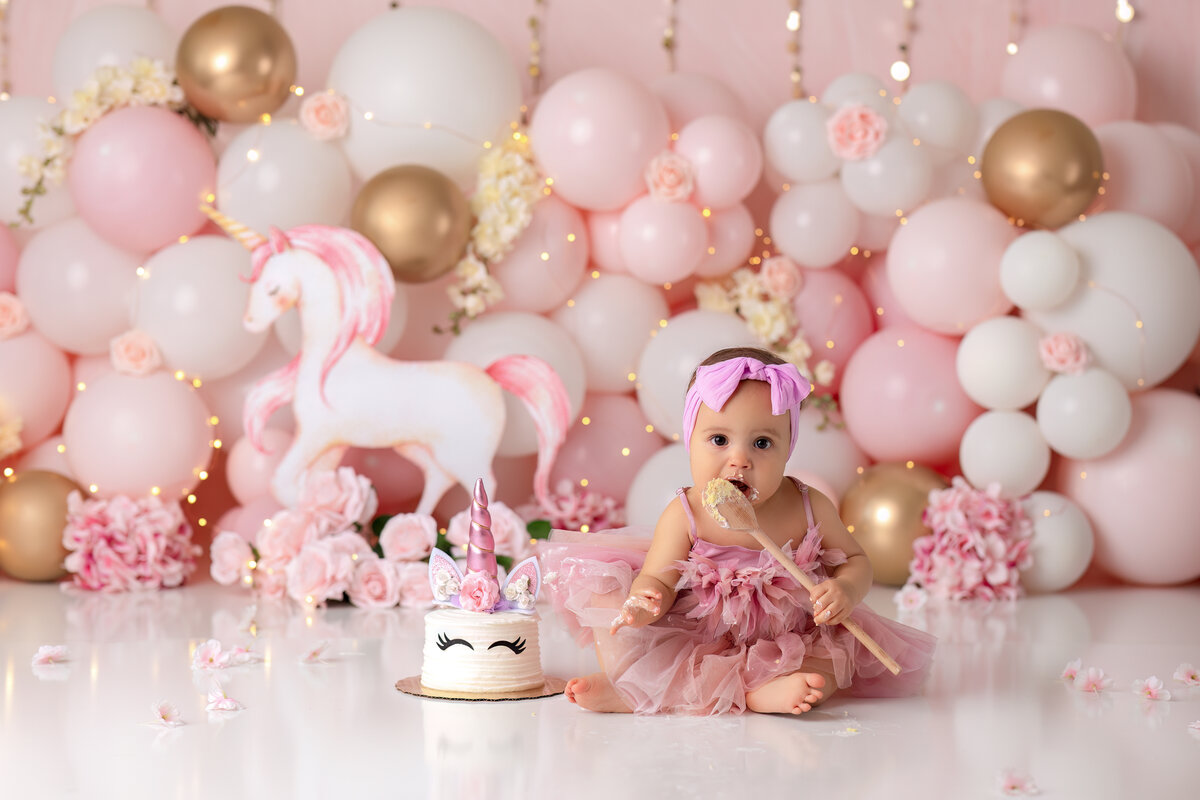 One year old Tampa baby enjoying a personalized luxury cake smash session with beautiful unicorn decorations