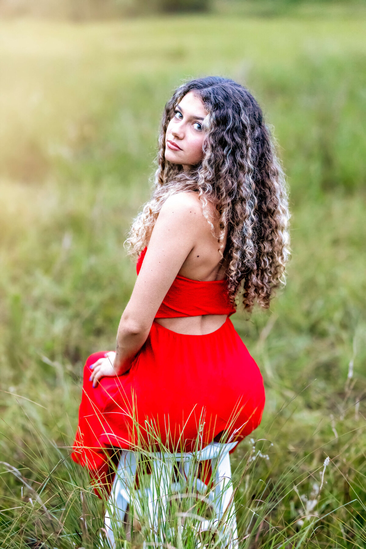 Senior girl sitting casually on a stool in an open field during Winter Garden senior portraits