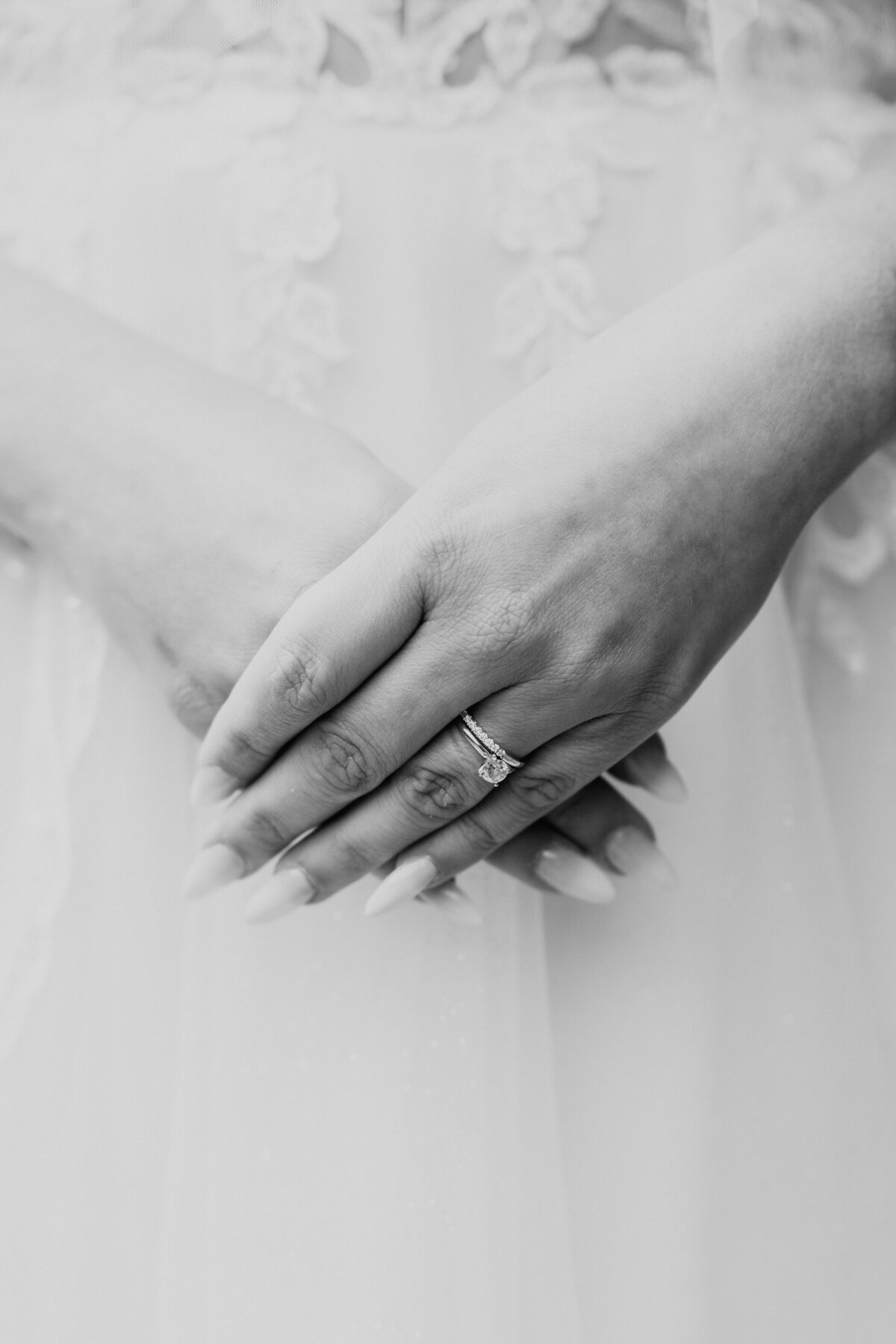Close-up of bride’s hands and wedding ring on lace dress
