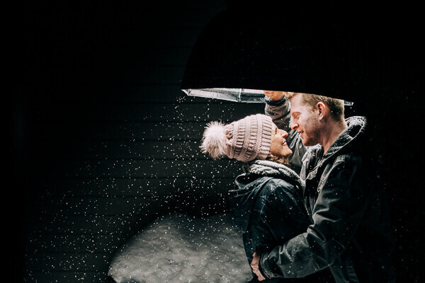 A romantic photo of Kate Simpson, Minnesota photographer, with her husband, outside on a snowy day, with dramatic lighting.
