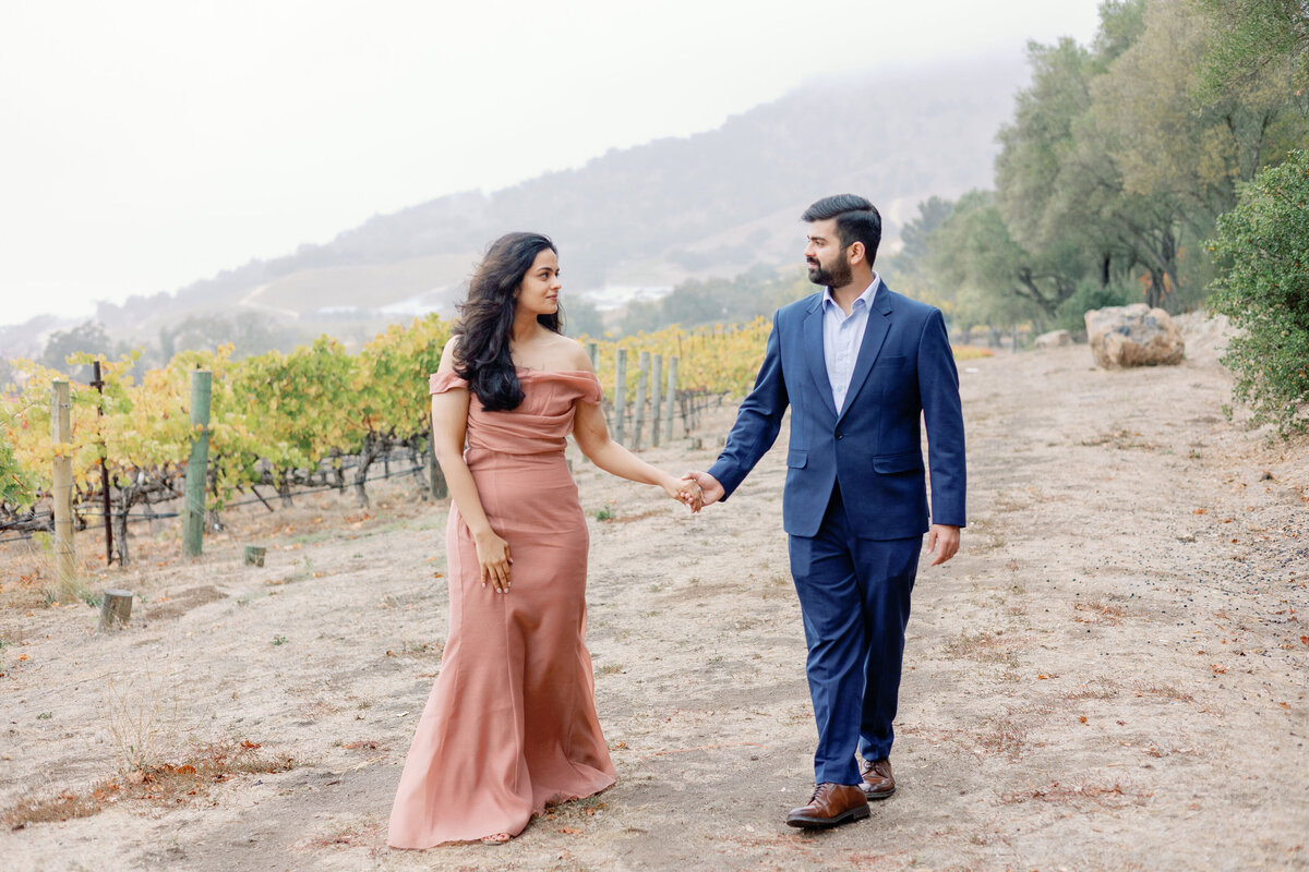 Napa engagement pictures with man and woman holding hands and smiling at one another captured by bay area photographers