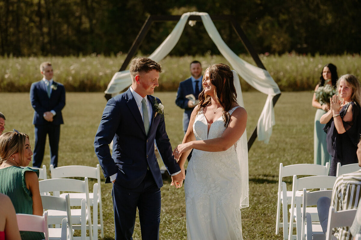 Newlyweds celebrating outdoors under a geometric arch