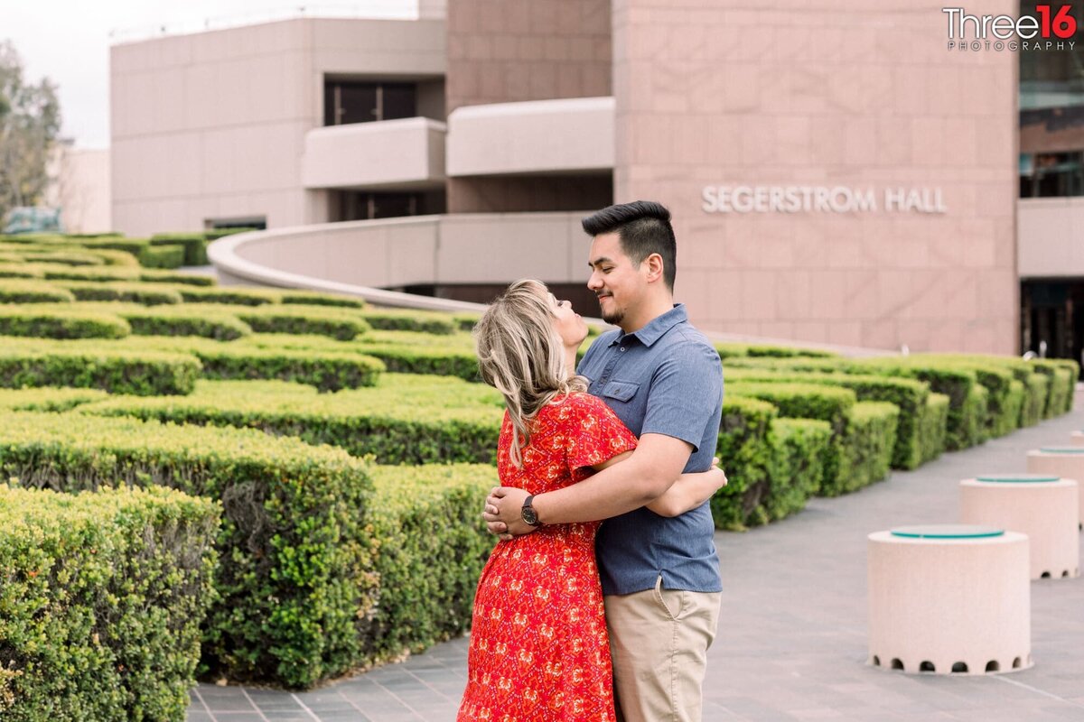 Future Bride and Groom embrace each other and look lovingly into each other's eyes on the grounds of the Segerstrom Center for the Art