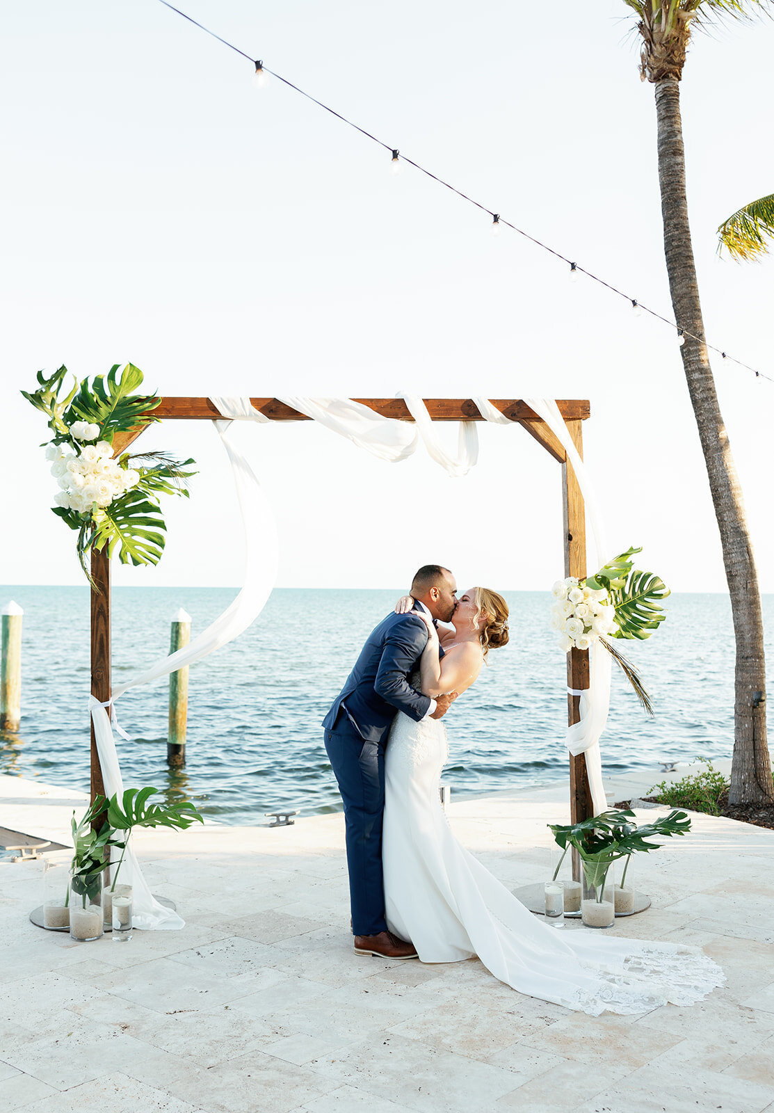 Sunset kiss under the wedding arch at La Siesta Marina Resort, beautifully captured by Claudia Amalia Photography.