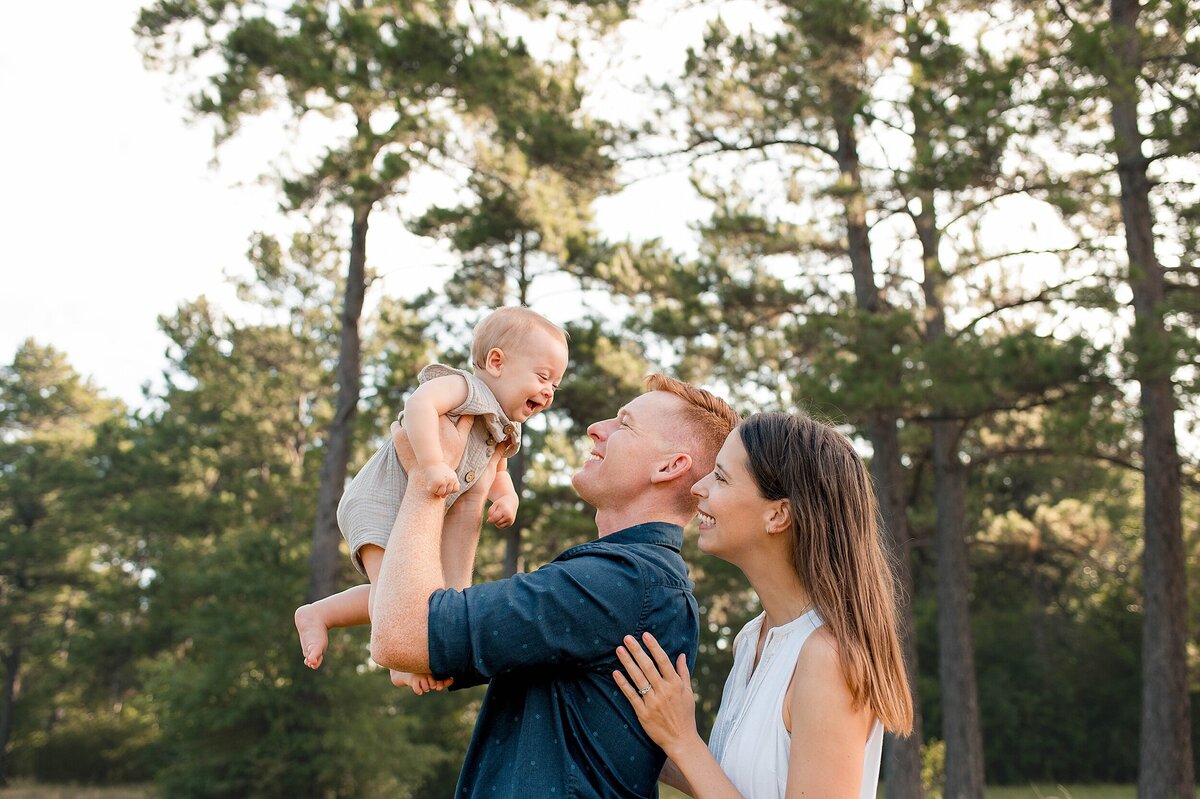 Parents holding young baby in the air by Cypress Texas Photographer