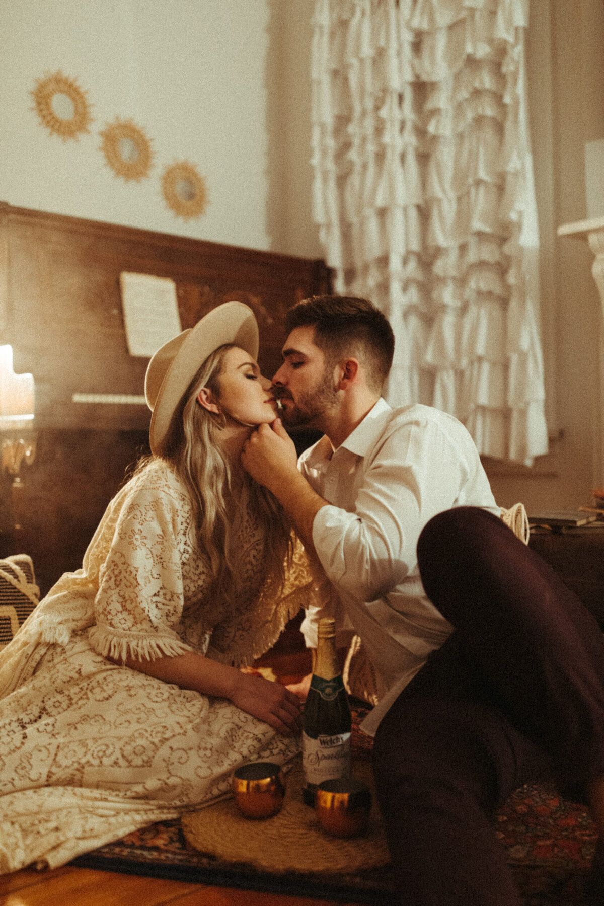 Groom pulling bride in for a kiss while sitting on the floor at their intimate Airbnb reception after their elopement