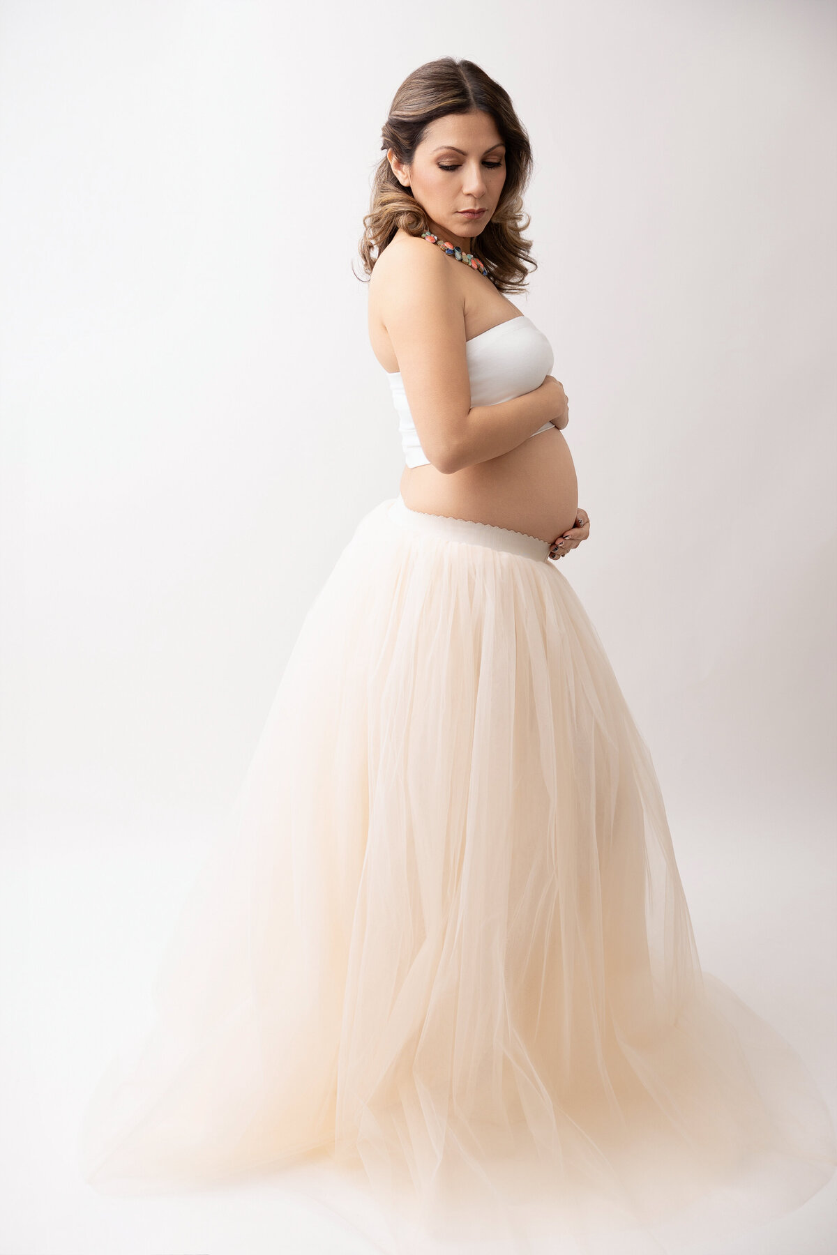 Pregnant woman wearing a wearing a white tube top and light-colored pink skirt